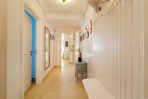A hallway with a blue door, a mirror, a small table with a black object, and a radiator.