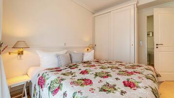 A bedroom with a bed, two wall-mounted lamps, a nightstand, and a door to a bathroom.