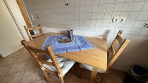 Una mesa de comedor de madera con un mantel azul, rodeada de sillas de madera.