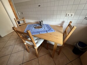 Een houten eettafel met een blauwe tafelkleed, omringd door houten stoelen.