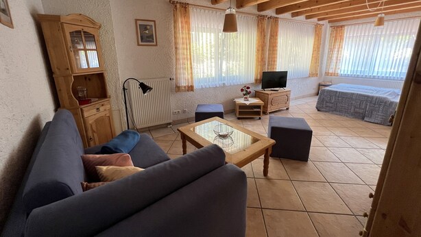 Una sala de estar acogedora con un sofá, una mesa de centro, un televisor y un aparador de madera.