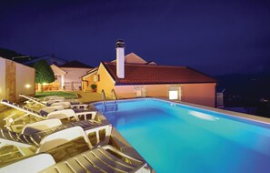 Relax by the pool surrounded by lounge chairs and a low wall.