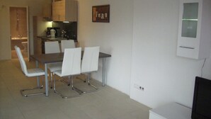 A compact living space with a dining area, kitchenette, and a TV. - VV 21; 3-space; mezzanine; Balcony; 78m² - Villa Vogelsang (Sierksdorf)