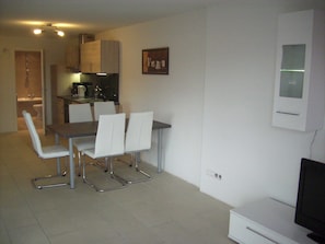 A compact living space with a dining area, kitchenette, and a TV.