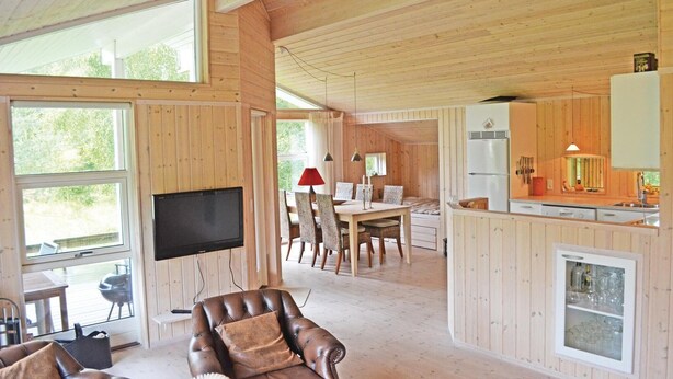 Un salón amplio con un televisor grande, muebles de madera y una zona de comedor con mesa y sillas.