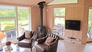 Una habitación acogedora con un ventanal grande, dos sillones de cuero, chimenea y televisor de pantalla plana en la pared.