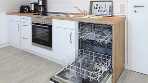 Una cocina moderna con armarios blancos, encimera de madera, horno empotrado, lavavajillas y cafetera.