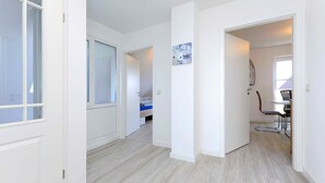 Un pasillo con una cama, una silla y una mesa en una habitación.
