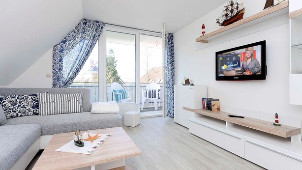 Una sala de estar moderna con un sofá gris, una mesa de centro de madera y un televisor montado en la pared.