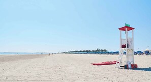 A beach with a lifeguard tower, a red kayak, and beach umbrellas.
