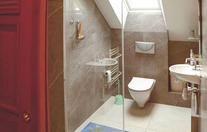 Un baño moderno con cabina de ducha de vidrio, inodoro, lavabo y toallero.