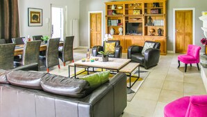 Un salon comprenant un canapé, des fauteuils, une table basse et une bibliothèque.