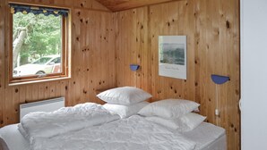 A wooden-paneled room with a bed, a radiator, a window with a view of a car, and a framed picture on the wall. - Gorgeous home in ålbæk with sauna (Ålbæk)
