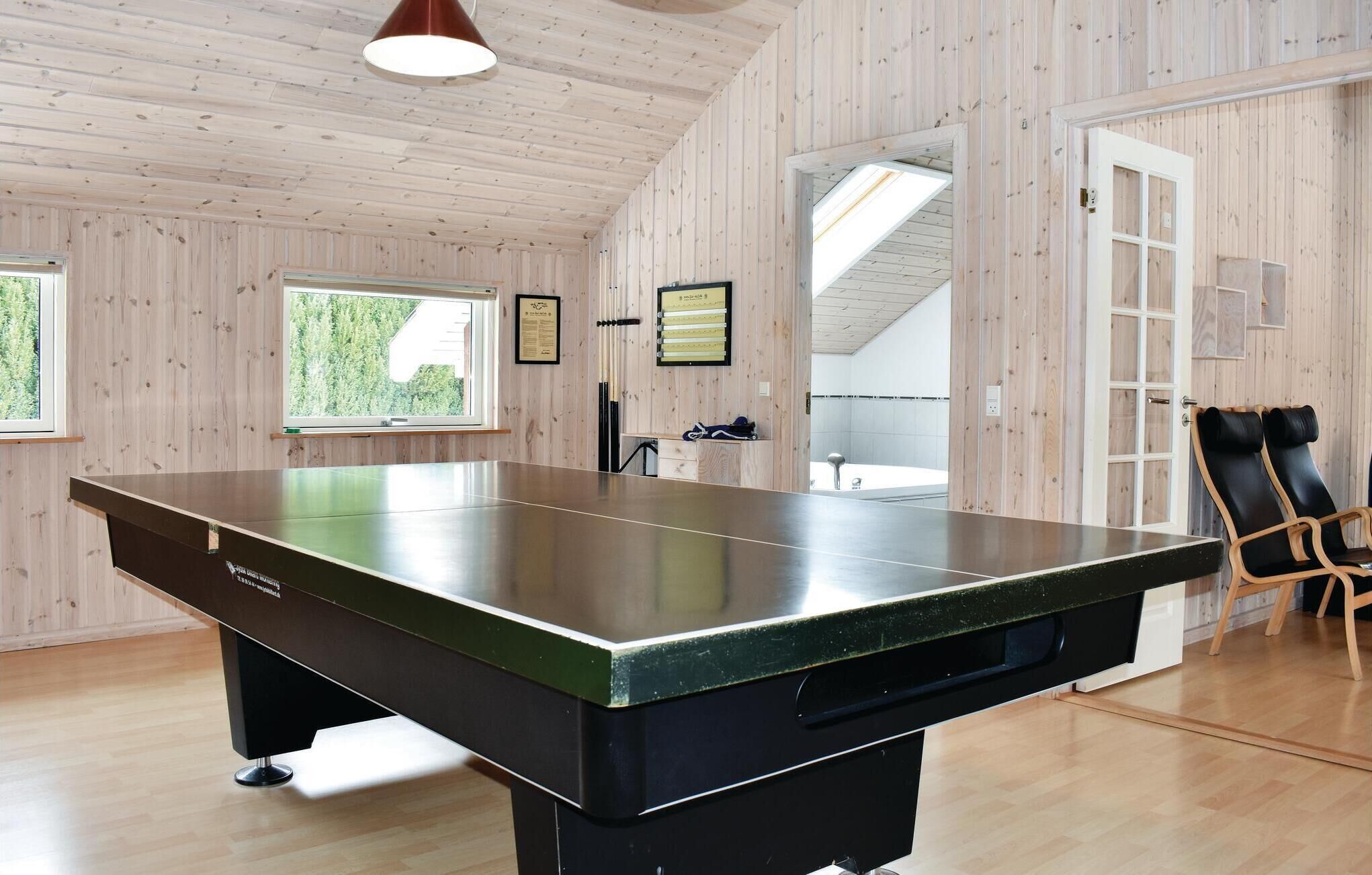 Una mesa de billar en una habitación con paredes de madera y techo alto.