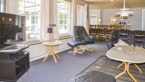 Un salon moderne avec un téléviseur, des fauteuils en cuir, une petite table ronde et un canapé.