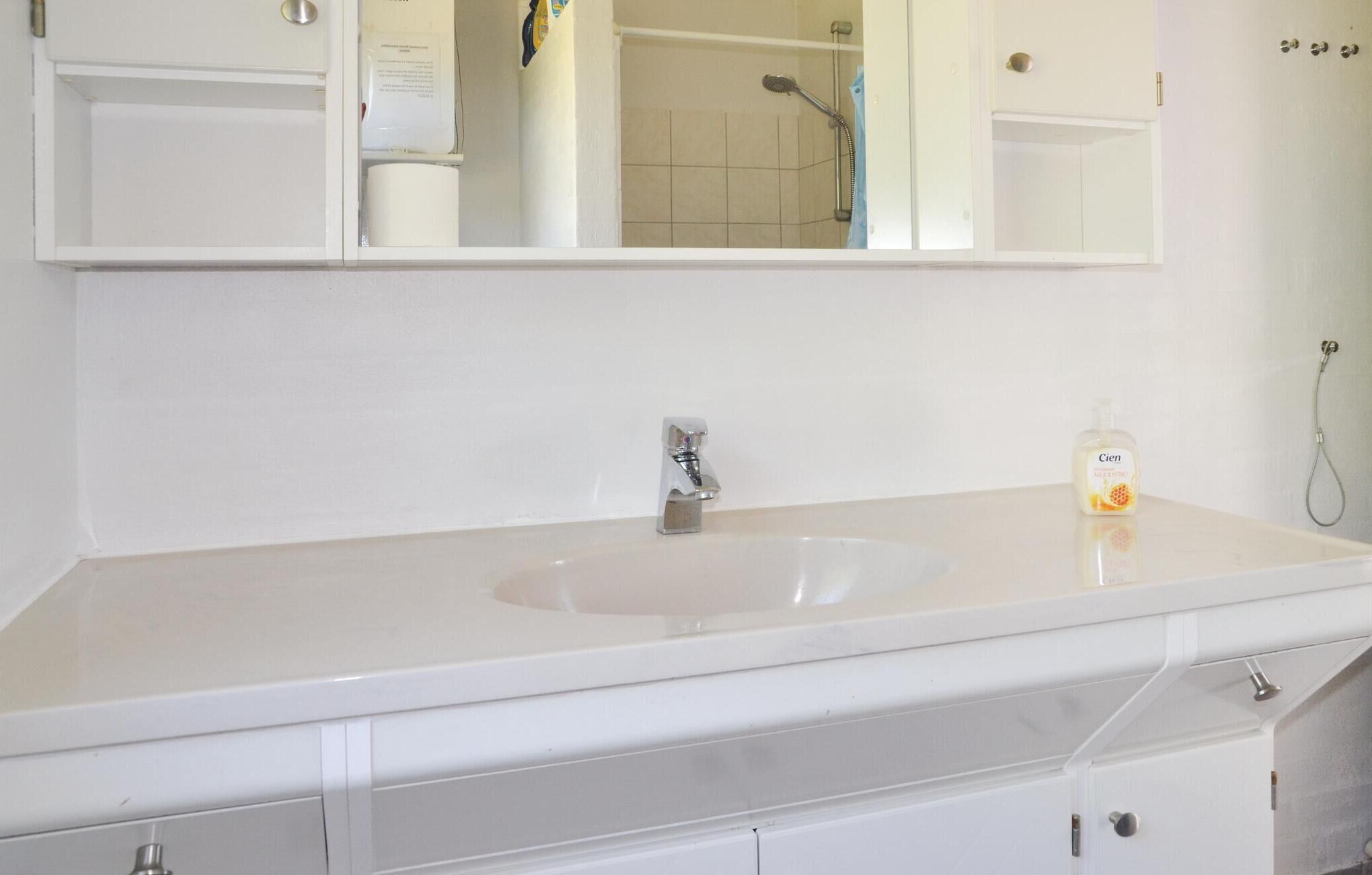Un baño con lavamanos blanco, espejo y ducha.