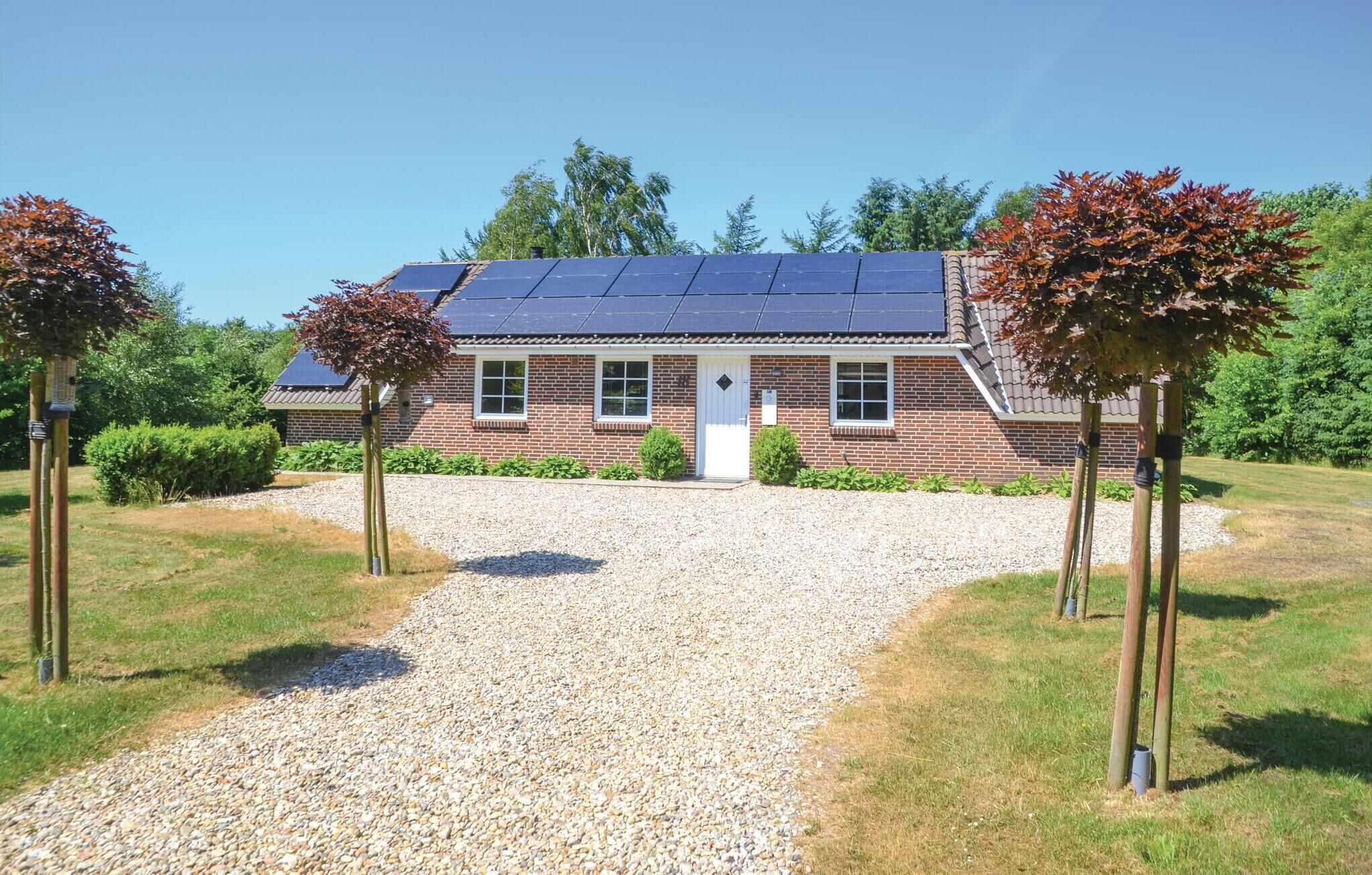 Un bâtiment en briques avec une allée en gravier et des panneaux solaires sur le toit.