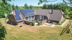 Une maison avec un toit en pente, des panneaux solaires, une terrasse et un jardin.
