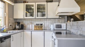 Une cuisine moderne avec des meubles blancs, un four à micro-ondes encastré et une machine à café.