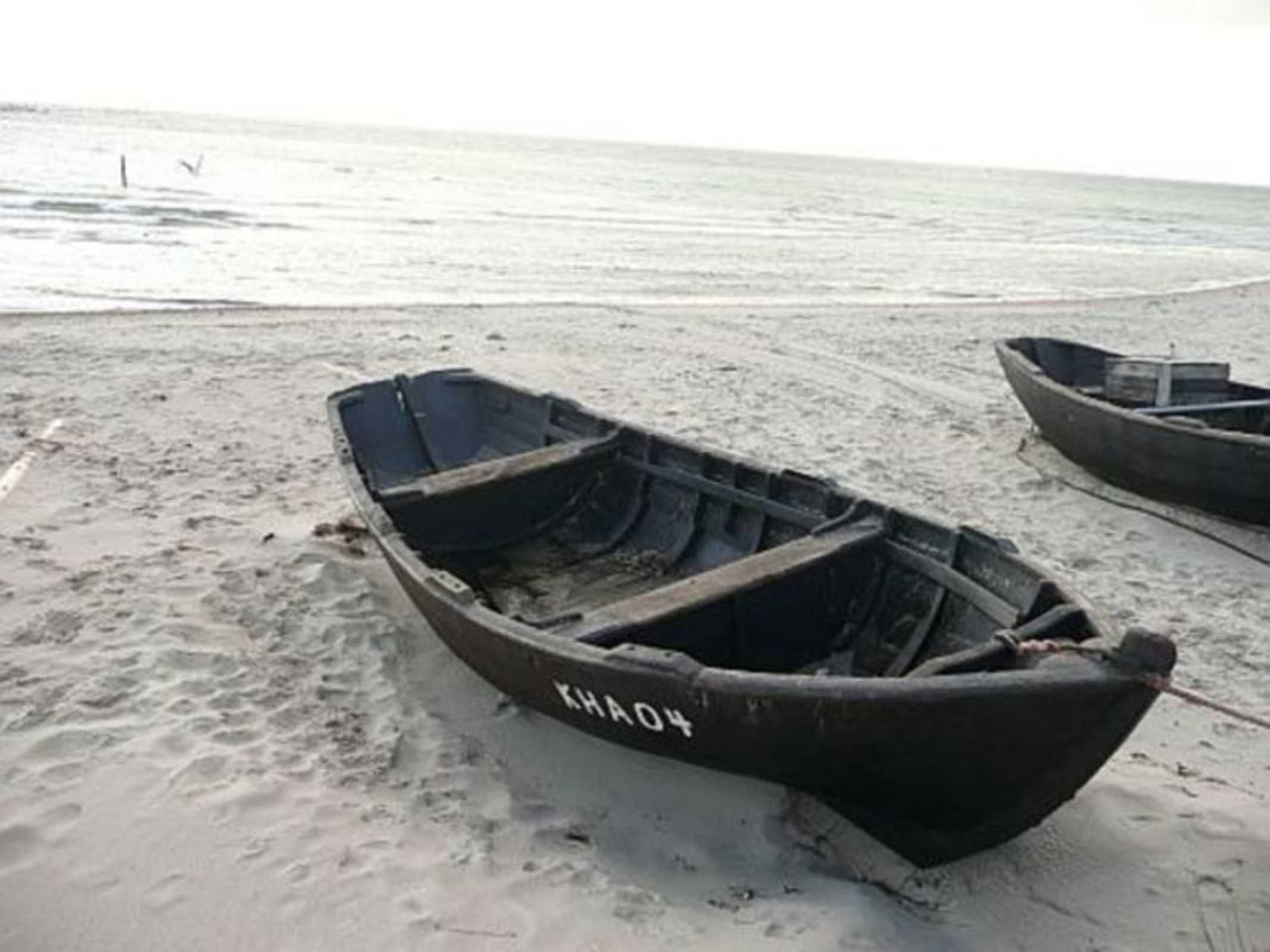 A rowboat with the number "KH04" on a sandy beach.