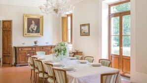 A dining room with a large table set for six, surrounded by chairs. There is a chandelier, a wooden cabinet, and a painting on the wall. - Beautiful home in Vicchio -FI- (Vicchio -FI-)