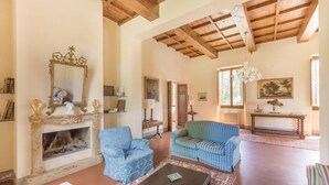 A spacious living room with a fireplace, blue upholstered furniture, and a classic chandelier. - Beautiful home in Vicchio -FI- (Vicchio -FI-)