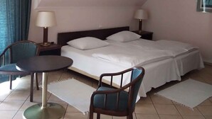 A hotel room with a bed, two bedside lamps, a chair, a small round table, and a ceiling light fixture. - Studio with internet, barbecue and pavilion (Gyenesdiás)