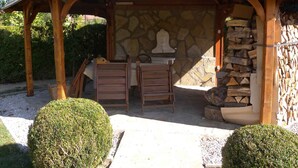 A covered outdoor seating area with stone walls and wooden furniture. - Studio with internet, barbecue and pavilion (Gyenesdiás)