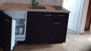 A kitchen with a built-in refrigerator, a sink, and a tiled backsplash. - Studio with internet, barbecue and pavilion (Gyenesdiás)