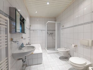 A modern bathroom with a bathtub, a shower, a sink, and a toilet. - Holiday house Plauer Burgblick - holiday house (Plau am See)