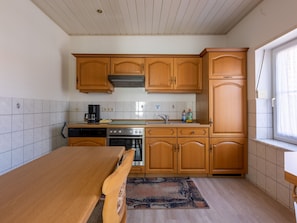 Una cucina compatta con mobili in legno, forno integrato e macchina per il caffè.