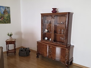 Ein Holzschrank mit Glastüren, ein kleiner Tisch mit einer Vase und eine Tasche auf dem Boden.