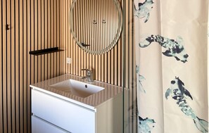 A bathroom with a wooden slat wall, a white sink with a mirror above it, and a floral shower curtain.