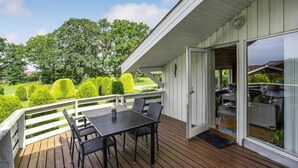 A wooden deck with a table and chairs, a white railing, and a view of a well-maintained garden and trees. - Amazing home in Egernsund with WiFi (Egernsund)