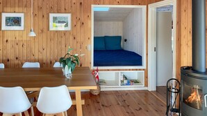 A cozy room with a bed, a dining table with chairs, a vase with flowers, and a fireplace. - Amazing home in Egernsund with WiFi (Egernsund)
