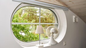 Ein Zimmer mit großem Fenster, einer weißen Lampe und einem weißen Ventilator.