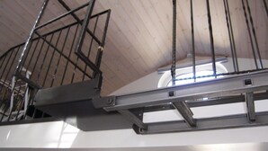 Eine Metalltreppe mit Handlauf, Holzboden und weißer Wand.