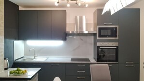 Eine moderne Küche mit dunklen Schränken, einer Edelstahl-Dunstabzugshaube, einer Mikrowelle und einem Backofen.