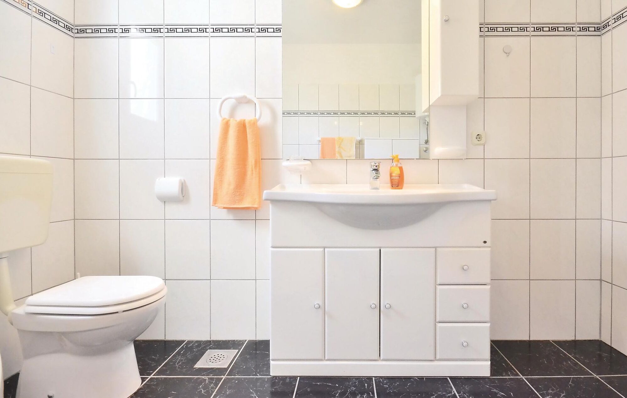 A bathroom with a toilet, a sink with a mirror, and a towel rack.