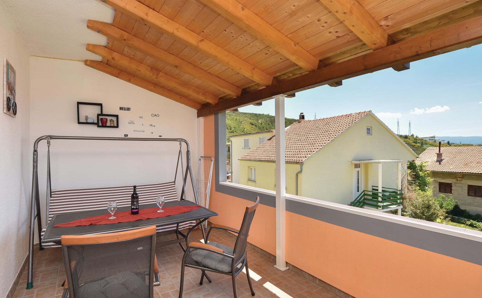 A balcony with a table and chairs, a view of houses, and a wooden ceiling.