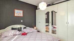 Ein Schlafzimmer mit Bett, Kleiderschrank, Spiegel und einer Pendelleuchte.