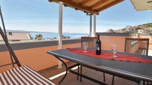 Ein Balkon mit Tisch, zwei Stühlen, einer Weinflasche und zwei Gläsern.