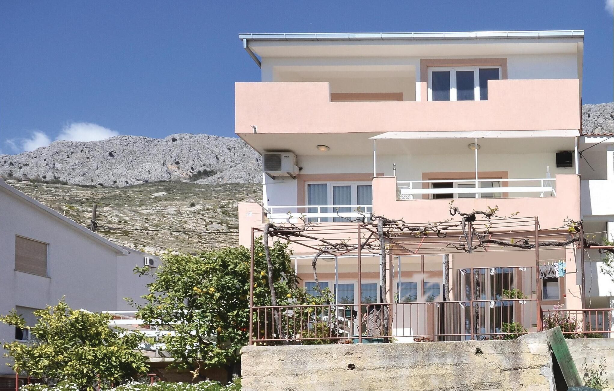 A two-story building with a balcony, a stone wall, and a mountainous backdrop.