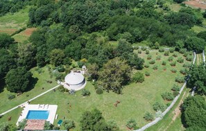 An aerial view of a property with a circular building surrounded by a lawn, a swimming pool, and a stone pathway. - Nice home in Manjadvorci (Manjadvorci)