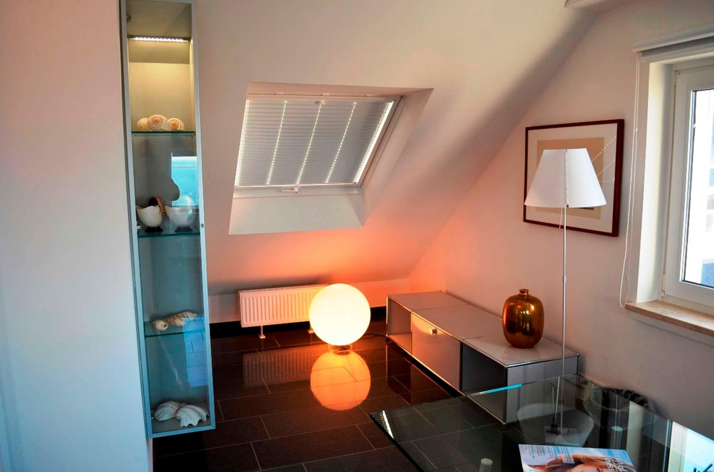 A modern room with a skylight, a glass cabinet, a radiator, and a lamp.
