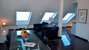 Un interior moderno con una mesa de comedor de vidrio, sofás negros y tragaluces.