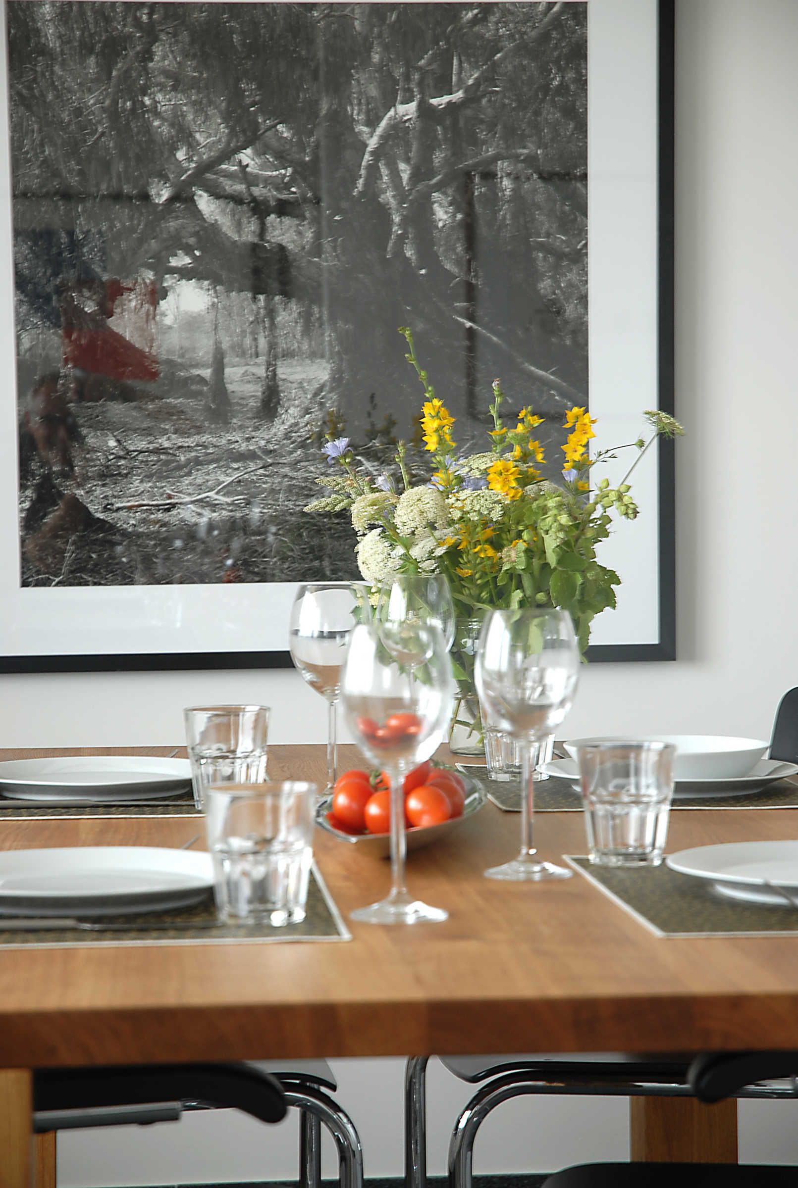 A dining table set with plates, glasses, and a vase with flowers.