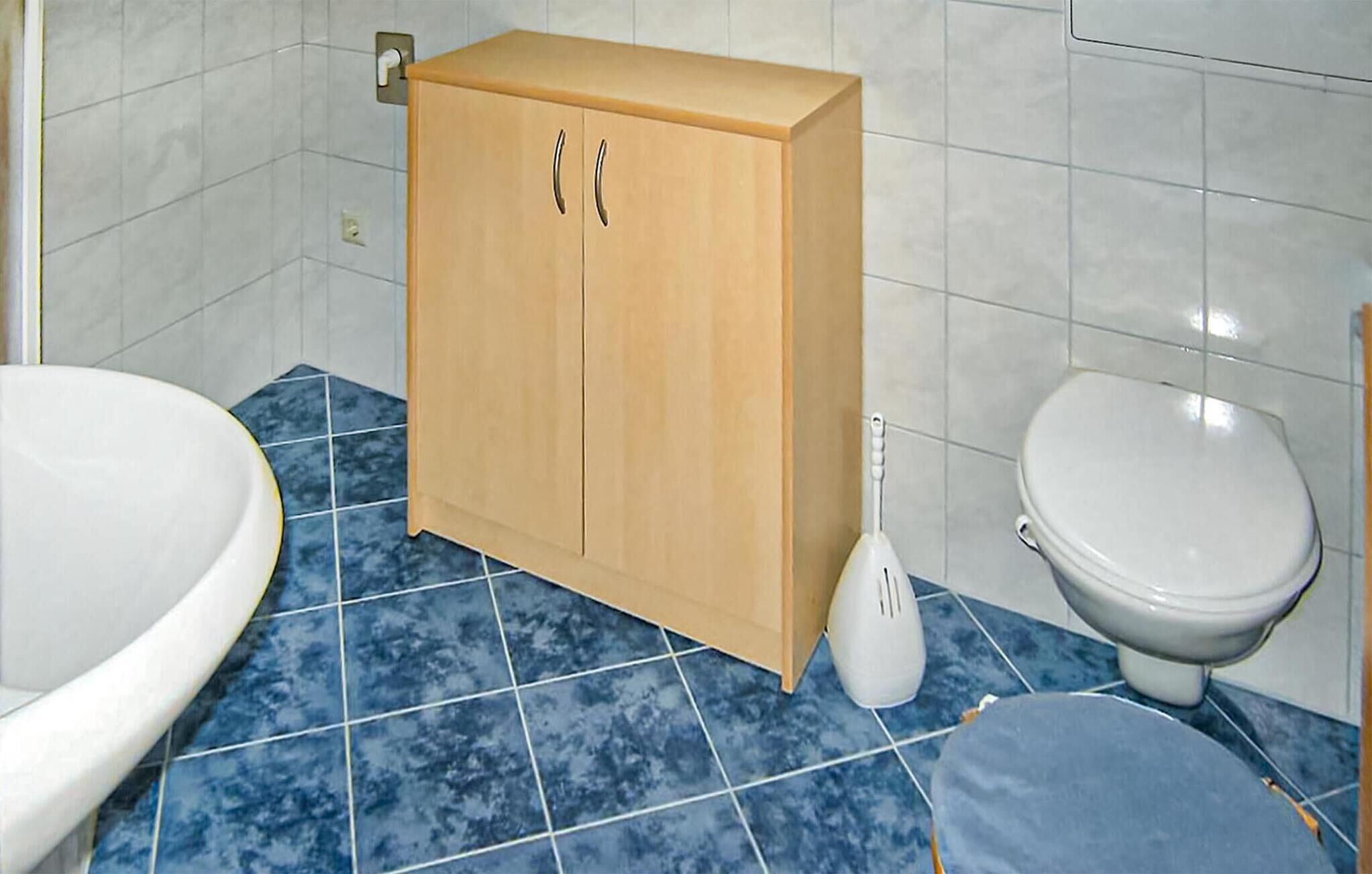 A bathroom with a wooden cabinet, a toilet, and a sink.