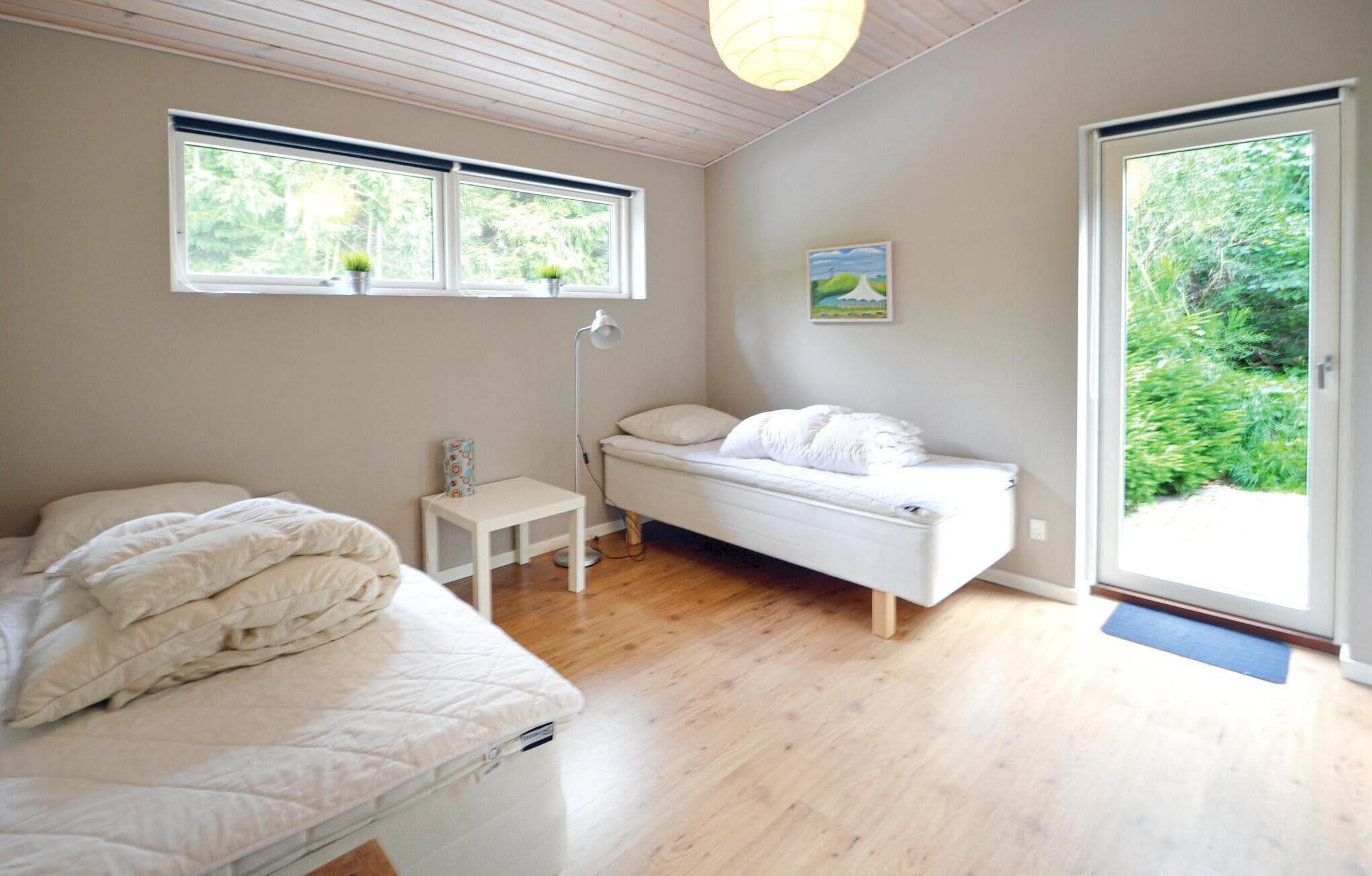 Een slaapkamer met een bed, een klein nachtkastje, een raam en een deur naar een tuin.