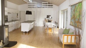 Une cuisine spacieuse avec un îlot central, un coin repas avec une table et des chaises, un canapé et une carte accrochée au mur.